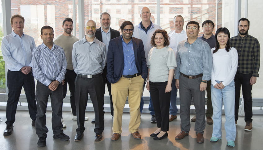 Group of people stand in front of a window smiling at the camera