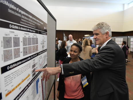 Dr. Roy Jensen Points at a poster with Harmony Saunders at the KU Cancer Center Research Symposium